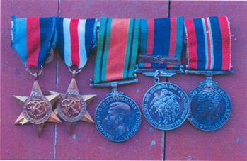 Five military medals displayed on a red surface. Three stars and two circular medals, each with colorful ribbons, evoke honor and history.
