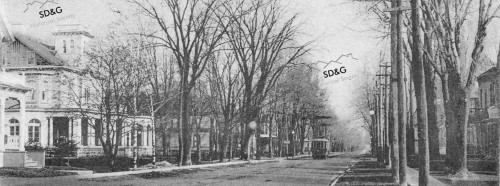 Historic black-and-white photo of a tree-lined street with a vintage streetcar, Victorian houses, and bare trees, conveying a serene, nostalgic atmosphere.