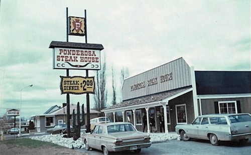 Vintage photo of Ponderosa Steak House with a sign advertising $2.09 steak dinner. Classic cars parked outside, creating a nostalgic feel.