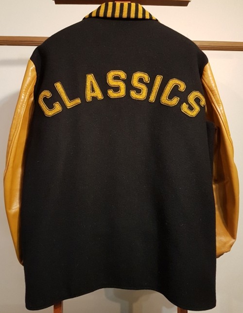 Black varsity jacket with yellow leather sleeves and "CLASSICS" stitched in bold yellow letters on the back. The tone is vintage and nostalgic.