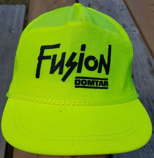 Bright yellow cap with "Fusion Domtar" printed in black on the front. The cap has a light decorative chain across the brim.
